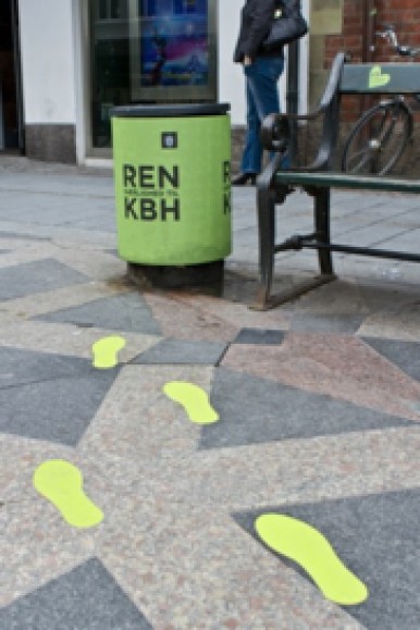 Des pas jaunes sont peints au sol en direction d'une poubelle